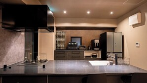 A modern kitchen with a gas stove, a built-in oven, a coffee machine, and a refrigerator. - United Resort Chatan Ocean Front (Chatan)