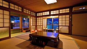 A traditional Japanese room with tatami flooring, a low table, and sliding doors.