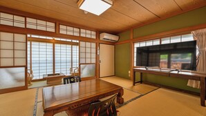 A traditional Japanese room with tatami flooring, a wooden table, a TV, and sliding doors.