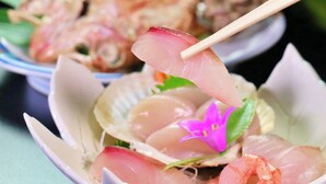 A bowl of sashimi with a purple flower garnish. - Katagiya (Kyotango)