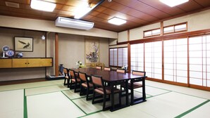A traditional Japanese meeting room with tatami mats, a wooden table, and shoji screens. - Katagiya (Kyotango)