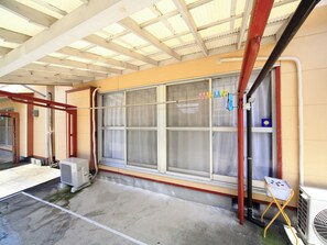A room with a large window, a red metal structure, and an air conditioning unit. - Kamon Inn Kotobuki (Izumi)