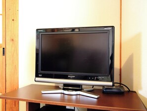 A flat-screen TV on a wooden table. - Kamon Inn Kotobuki (Izumi)