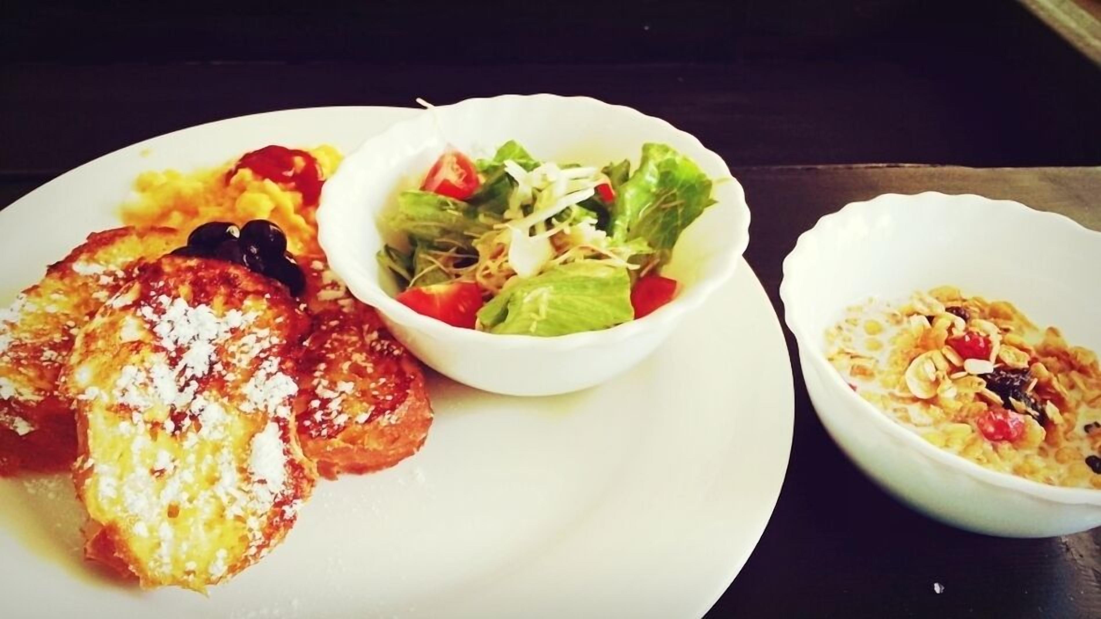 Un piatto con pane tostato, un'insalata e una ciotola di cereali.