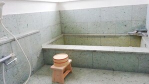 Un baño pequeño con bañera, un taburete de madera y una zona de ducha.