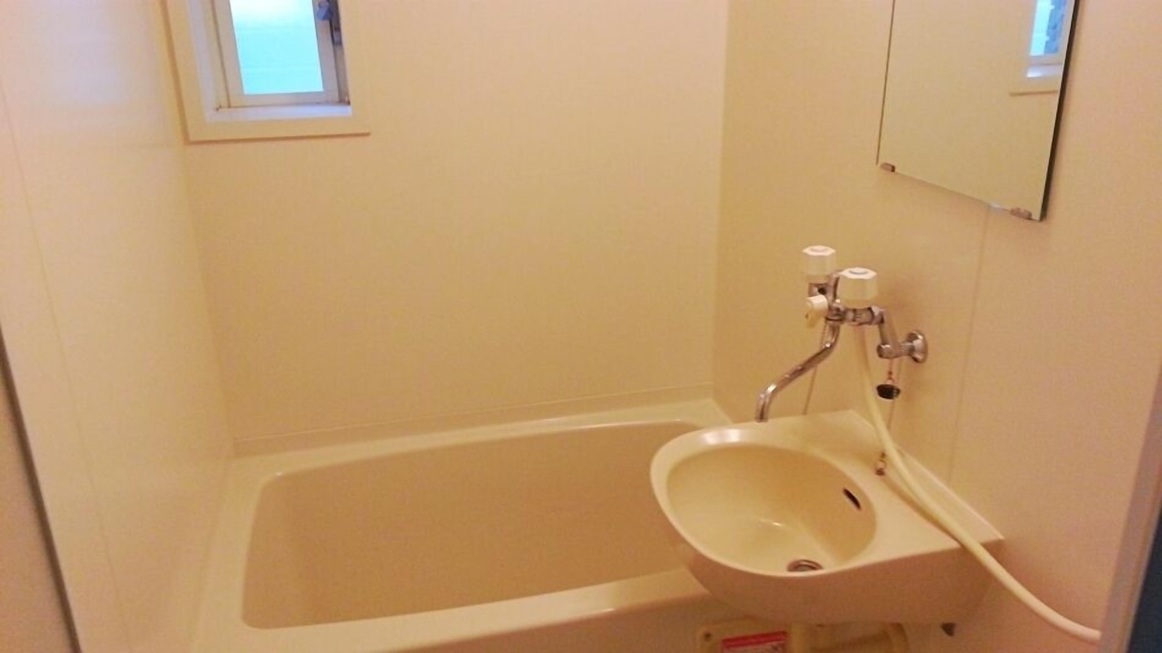 A small, single-bathroom with a bathtub, a sink, and a mirror.