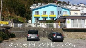 A building with multiple balconies and a parking area with two cars.