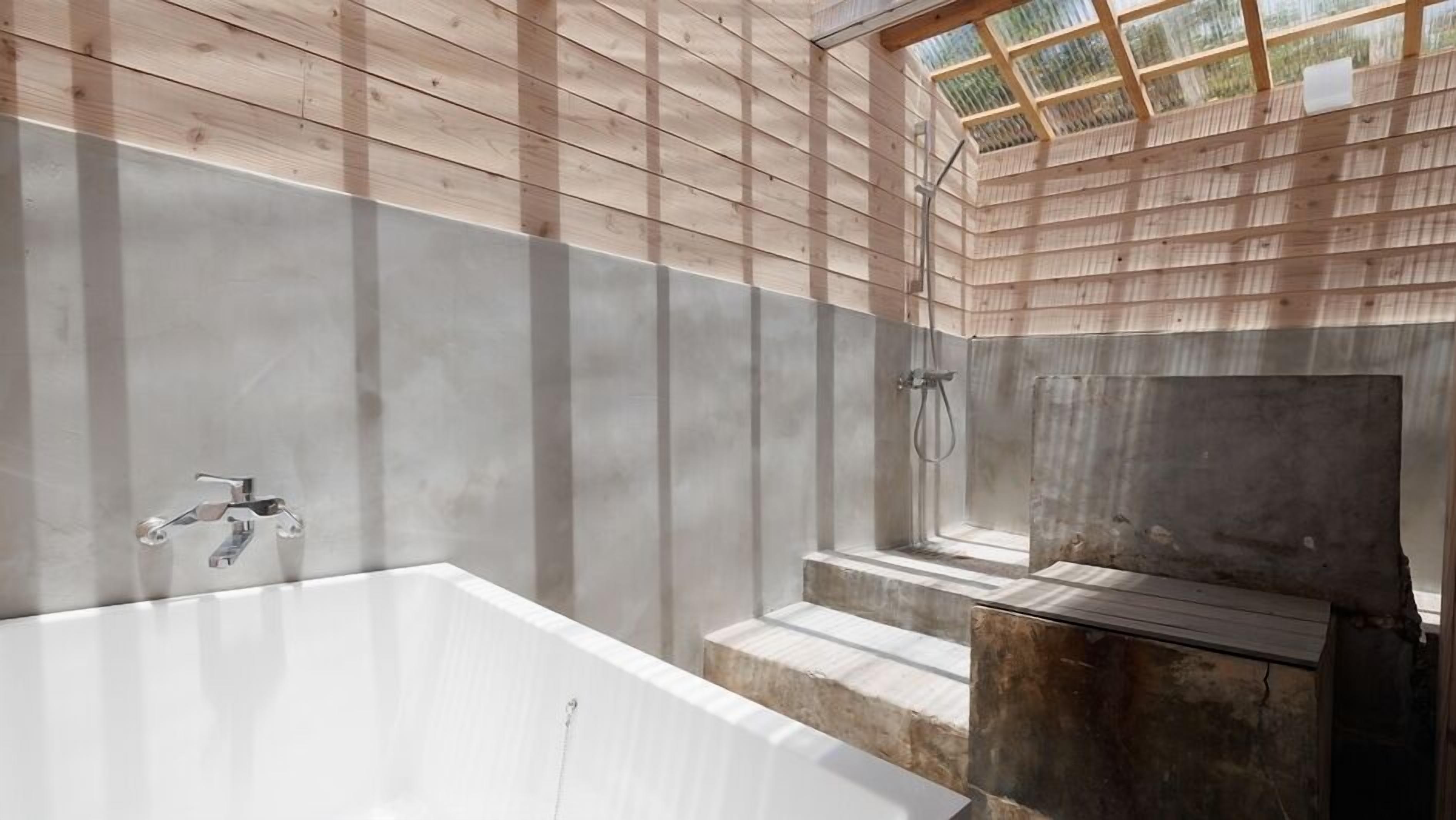 A bathroom with a large bathtub, a shower area, and a skylight.