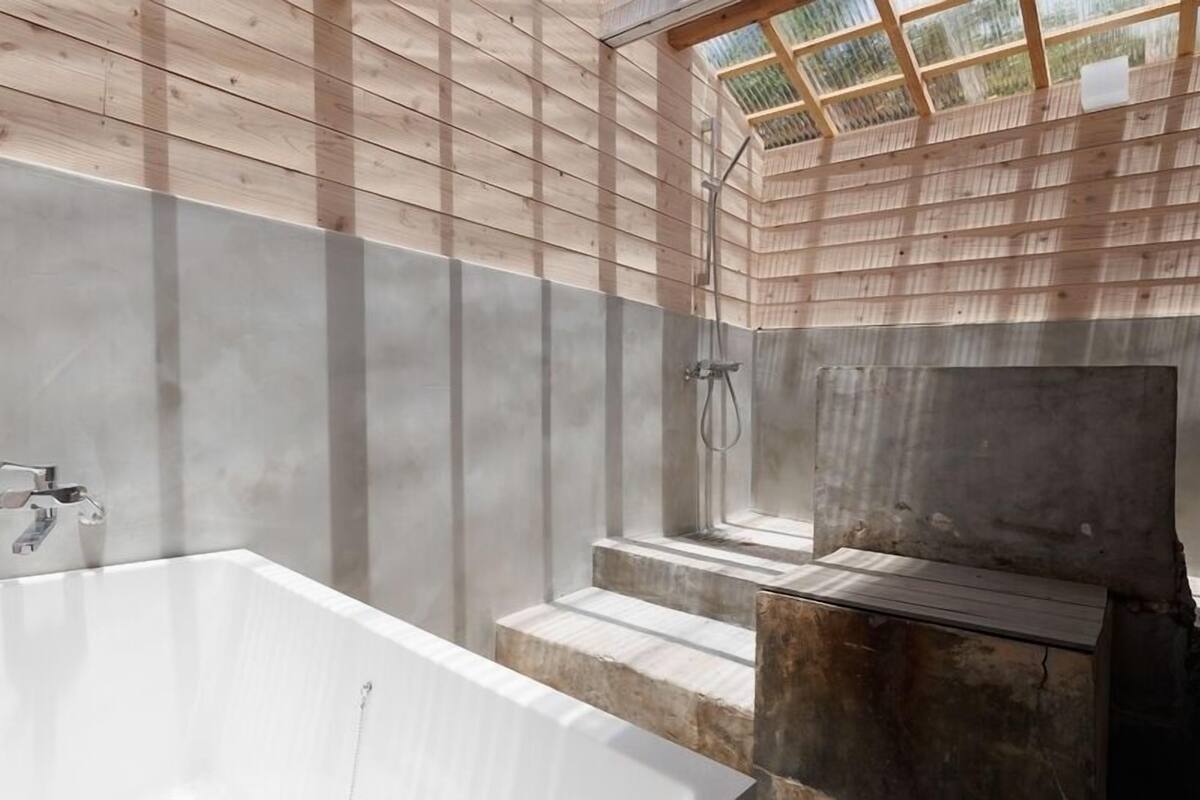Ein Badezimmer mit einer großen Badewanne, einer Duschkabine und einem Oberlicht.