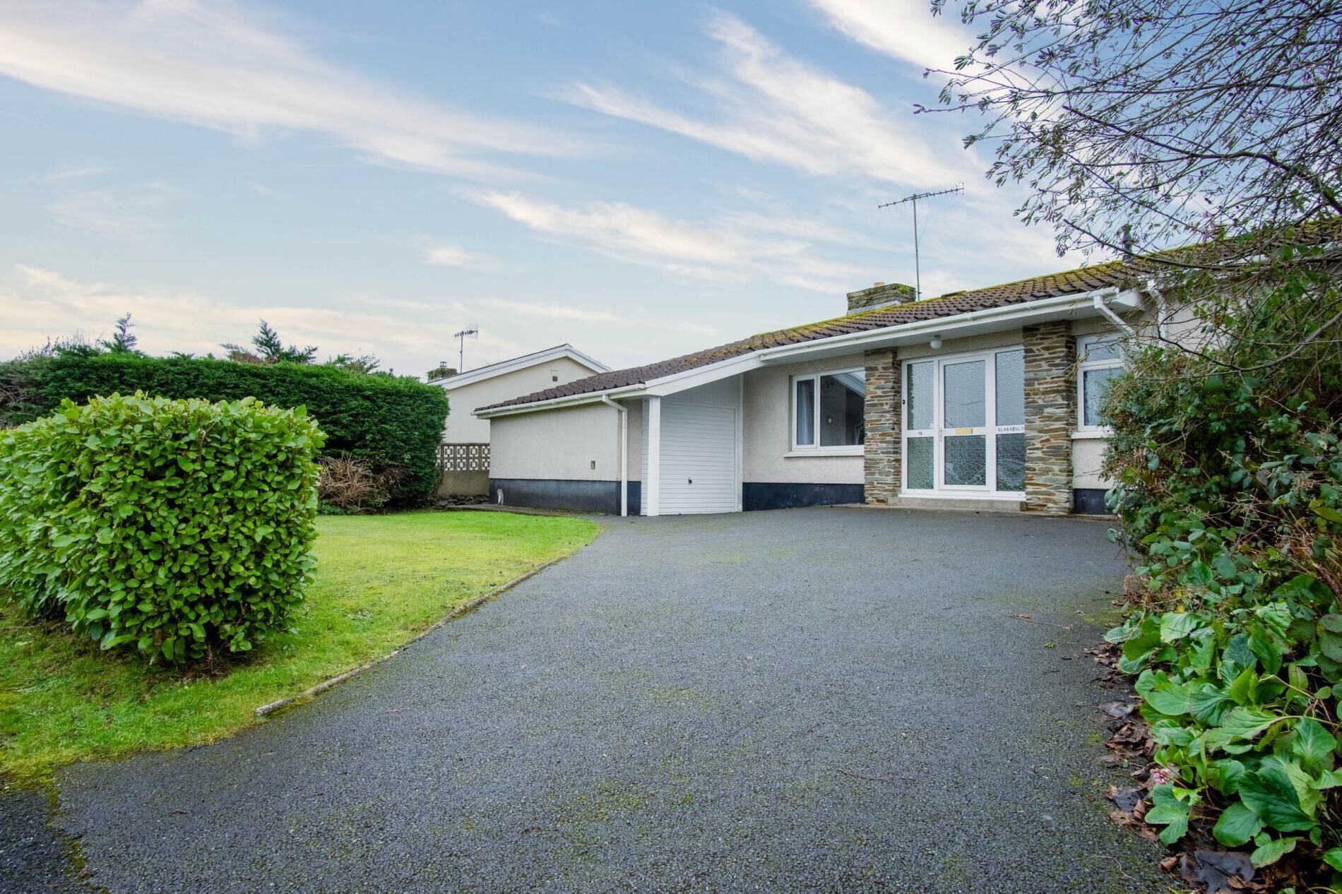 A single-story house with a paved driveway leading to a garage.
