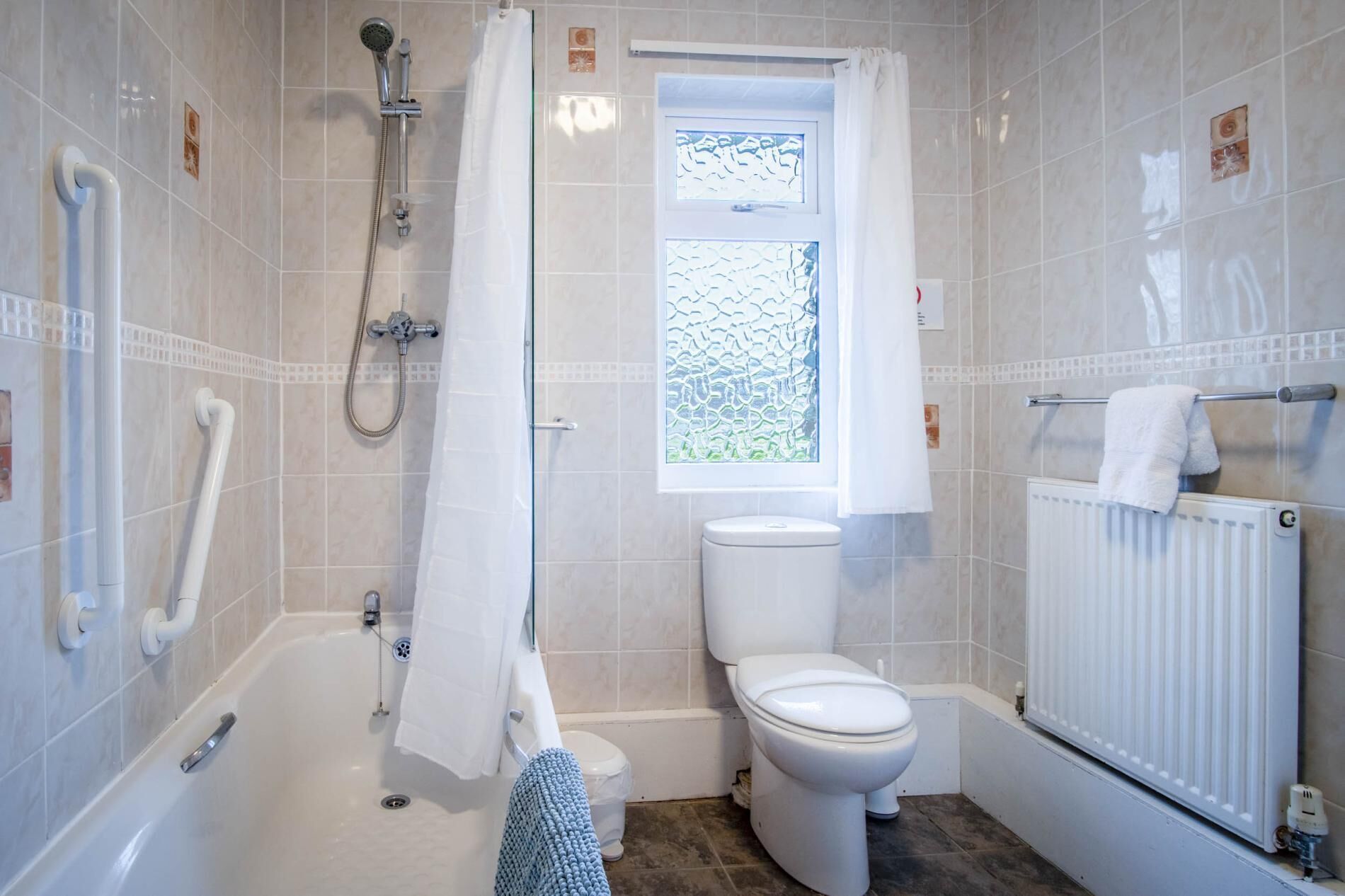 Ein Badezimmer mit einer Badewanne, Toilette und einem Fenster mit Milchglas.