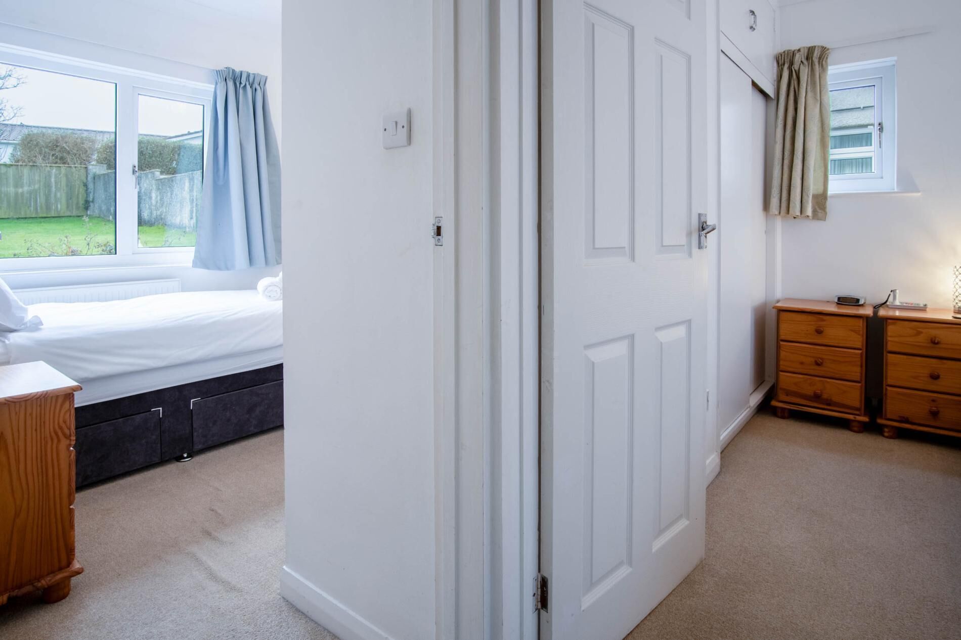 A bedroom with a bed, a wardrobe, a dresser, and a window with curtains.