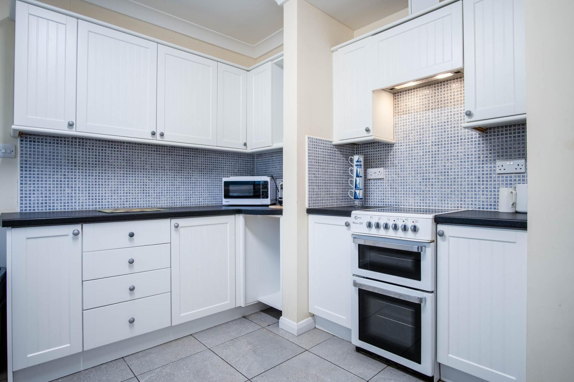 A kitchen with white cabinets, a microwave, and a stove.