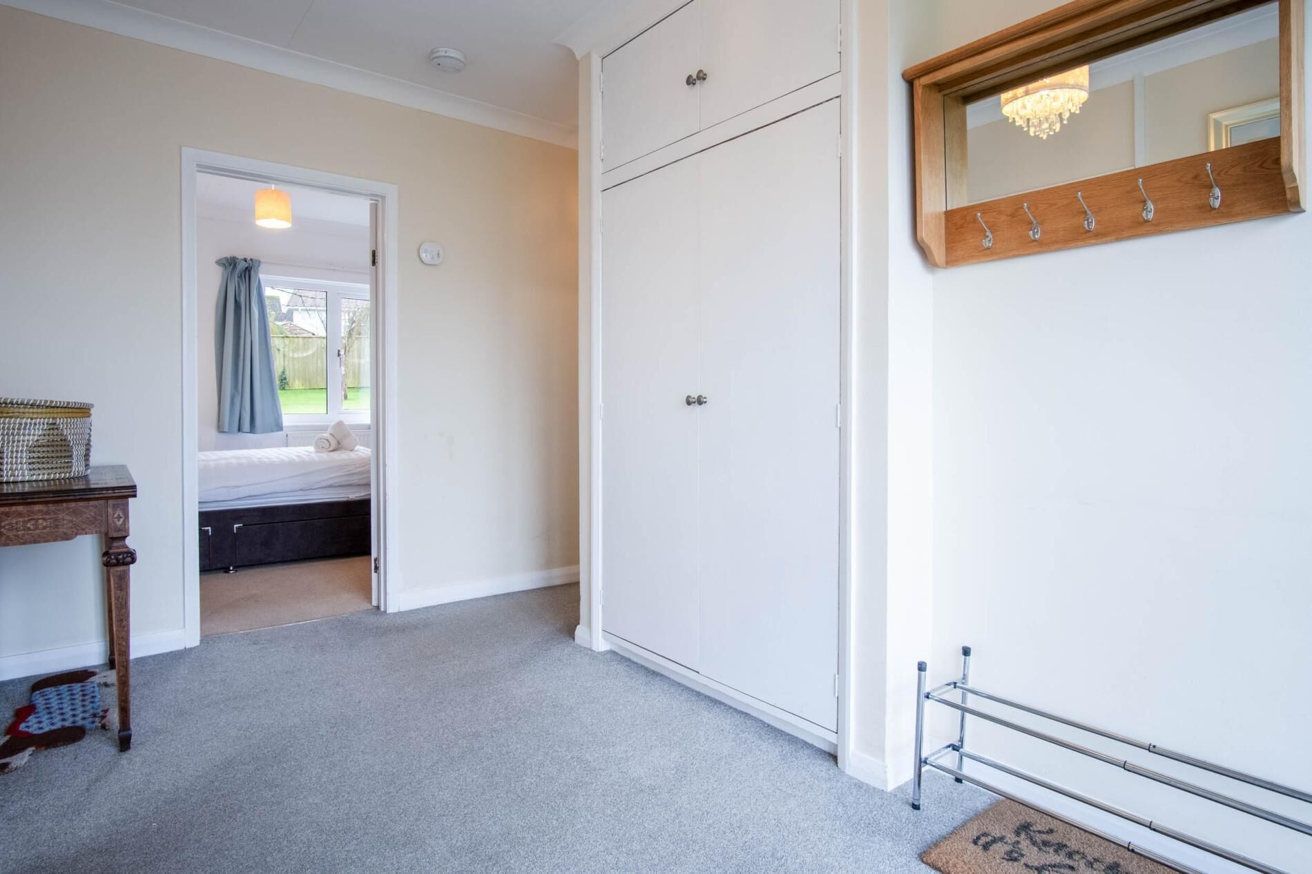 Une chambre à coucher avec un lit, une armoire, un miroir et une petite table.