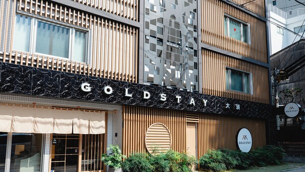 Fachada de hotel con un letrero que dice 'GOLDSTAY'.
