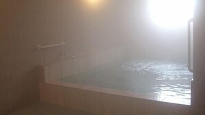 Een badkamer met een bad, een handdoekhouder en een zichtbare douche.