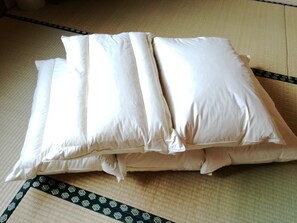 A tatami mat room with a bed and pillows. - Business Inn Mizuho Ryokan (Koriyama)