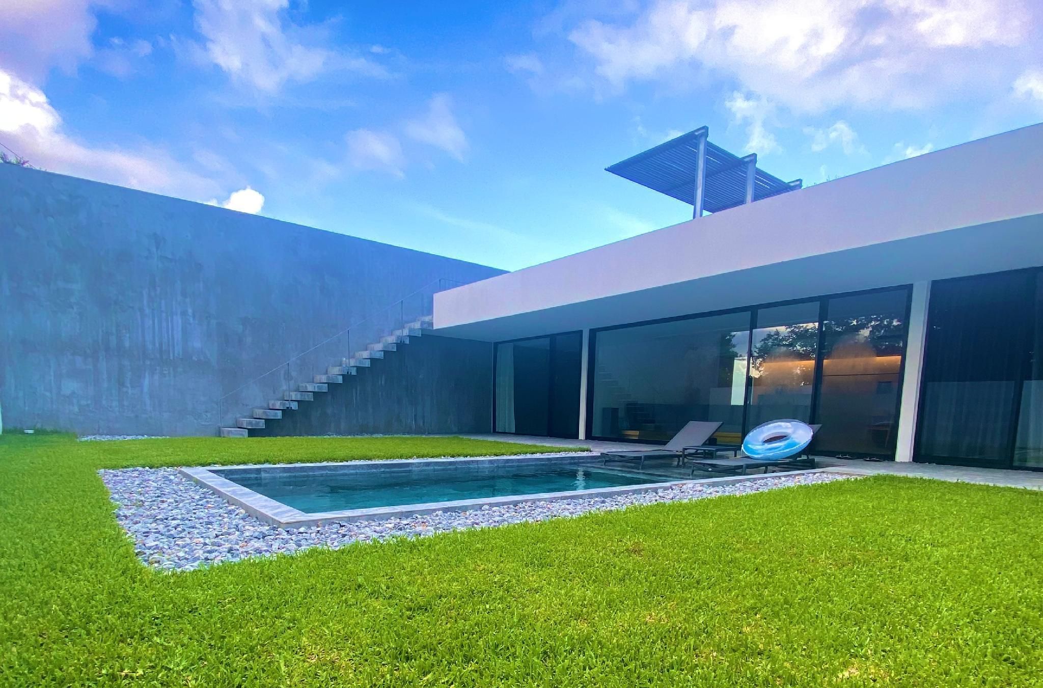 A modern house with a swimming pool, a grassy lawn, and a staircase leading to a second floor.