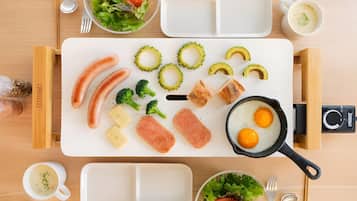 A meal setup with various foods and utensils on a wooden table.