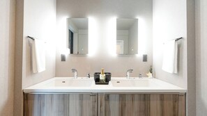 A modern bathroom with two sinks, a large mirror, and a wooden cabinet below. - Izumo Dogs (Izumo)
