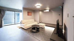 A modern living room with a sofa, ottoman, and coffee table. - Izumo Dogs (Izumo)