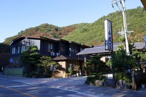 A traditional Japanese building with a dark exterior, a tiled roof, and a signboard. - Bandai Atami Onsen Yamashiroya (Koriyama)
