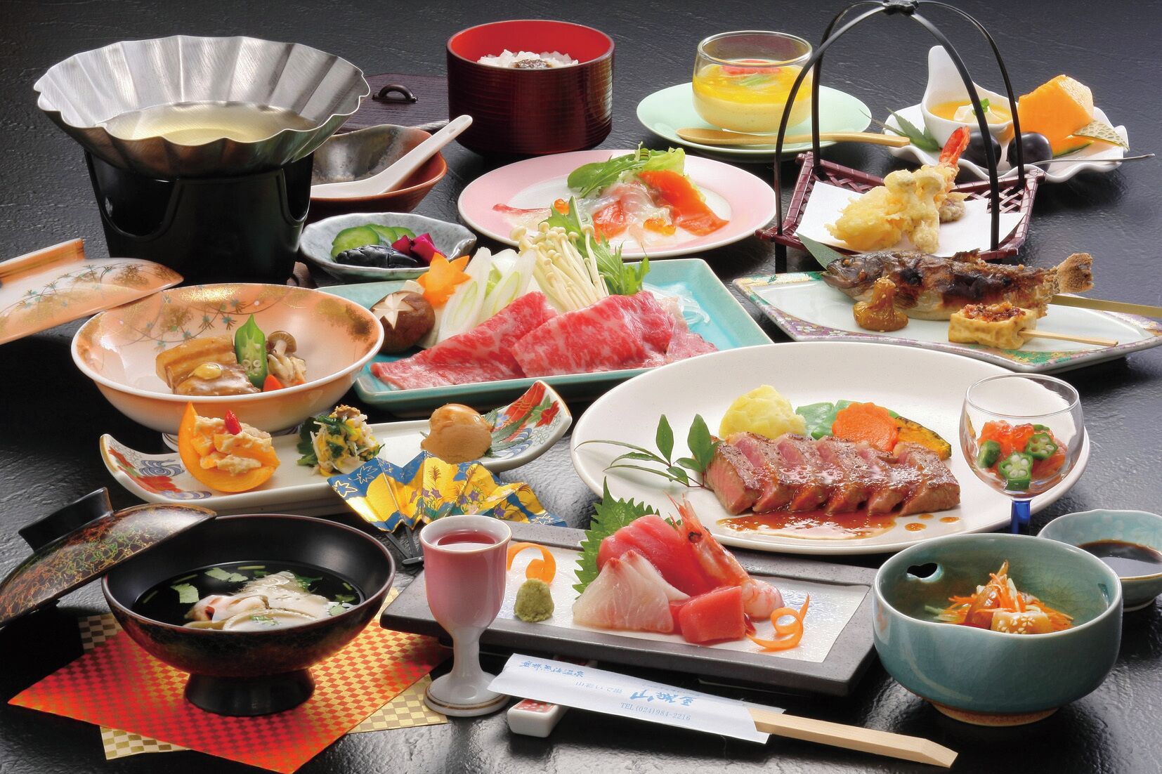Verschiedene japanische Gerichte, darunter Sushi, Sashimi und Tempura, serviert auf mehreren Tellern und Schalen.