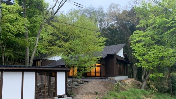 A traditional Japanese house with a wooden exterior, a stone pathway leading to the entrance, and lush greenery surrounding the property. - Myotoku-an (Kunisaki)