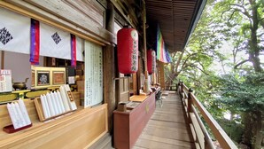 A traditional wooden building with a covered walkway, wooden benches, and red lanterns. - Myotoku-an (Kunisaki)