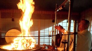 A chef performing a flambé with a large fire in a kitchen. - Myotoku-an (Kunisaki)