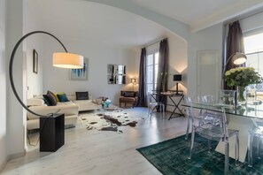 Ein modernes Wohnzimmer mit Sofa, Couchtisch und Essbereich mit Stühlen und einem Glastisch.
