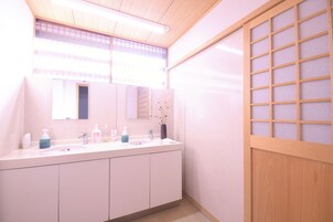 Un baño moderno con un tocador blanco, un espejo grande y una puerta corredera de madera.