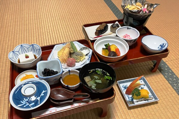 Uma refeição tradicional japonesa servida em um tatame, com diversos pratos, incluindo sopa, picles e uma pequena tigela de molho de soja.