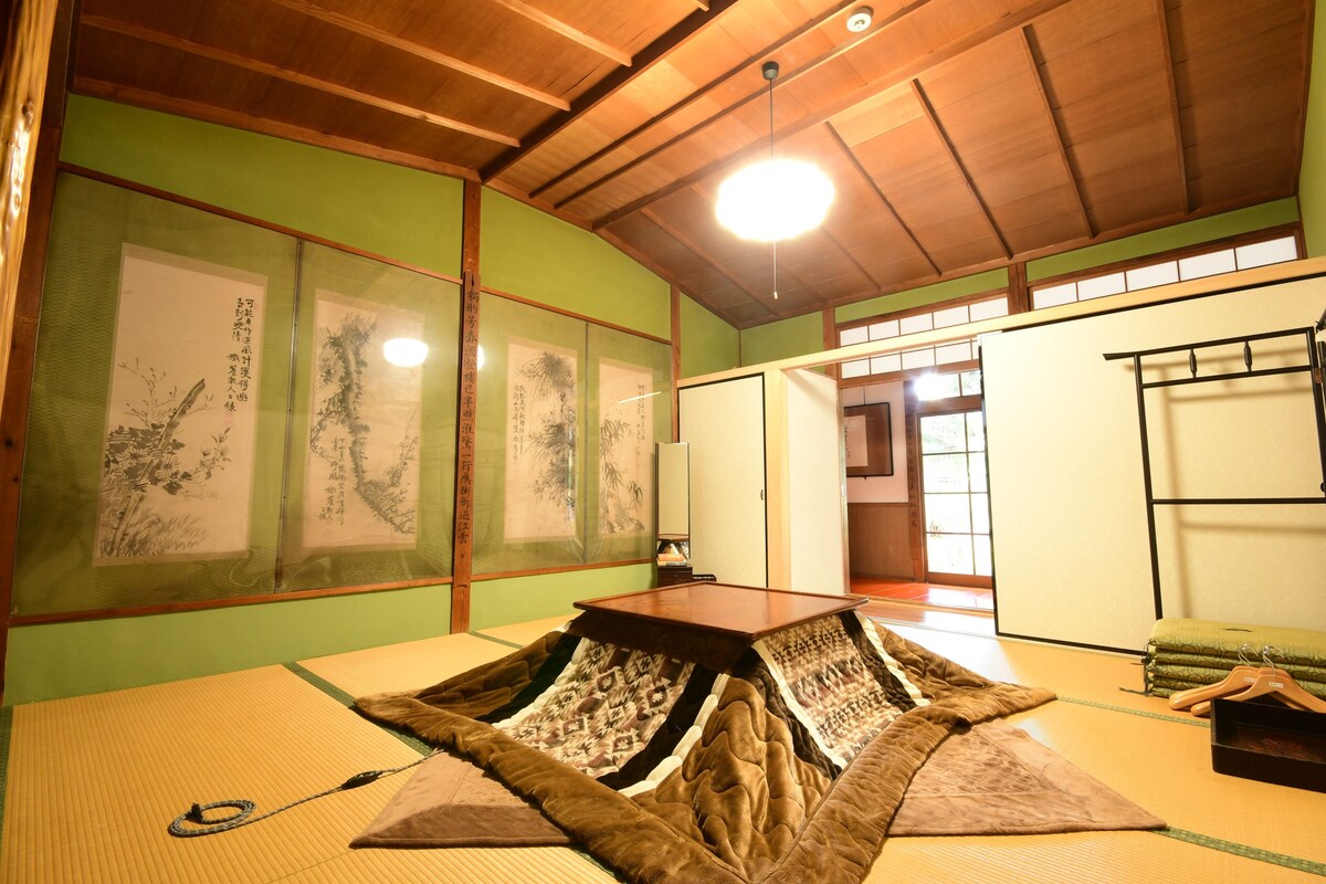 Ein Raum mit Tatami-Matten, Holzboden und einem Tisch aus Tatami-Matten, sowie eine traditionelle japanische Schiebetür.
