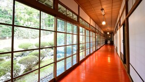 Un pasillo con ventanas amplias, techo de madera y suelo rojo.