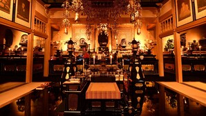 Una habitación ornamentada con decoración tradicional, que incluye un altar central, adornos colgantes y cuadros en las paredes.