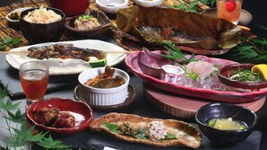 Variedad de platos que incluyen pescado, arroz y sopa, servidos sobre una mesa con un vaso de bebida.
