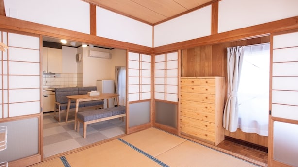 Ett traditionellt japanskt rum med tatamimattor på golvet, ett lågt träbord, en soffa och ett träskåp.
