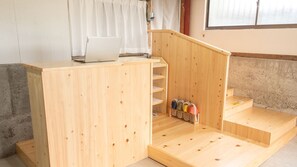 Eine Holztreppe mit einem Laptop darauf, die zu einem Raum mit einer Betonwand und einem Fenster führt.