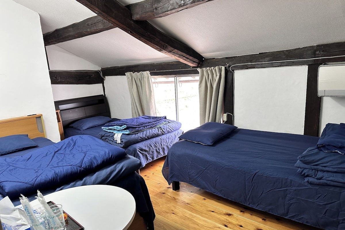 A room with two beds, a small table, and a window with curtains.