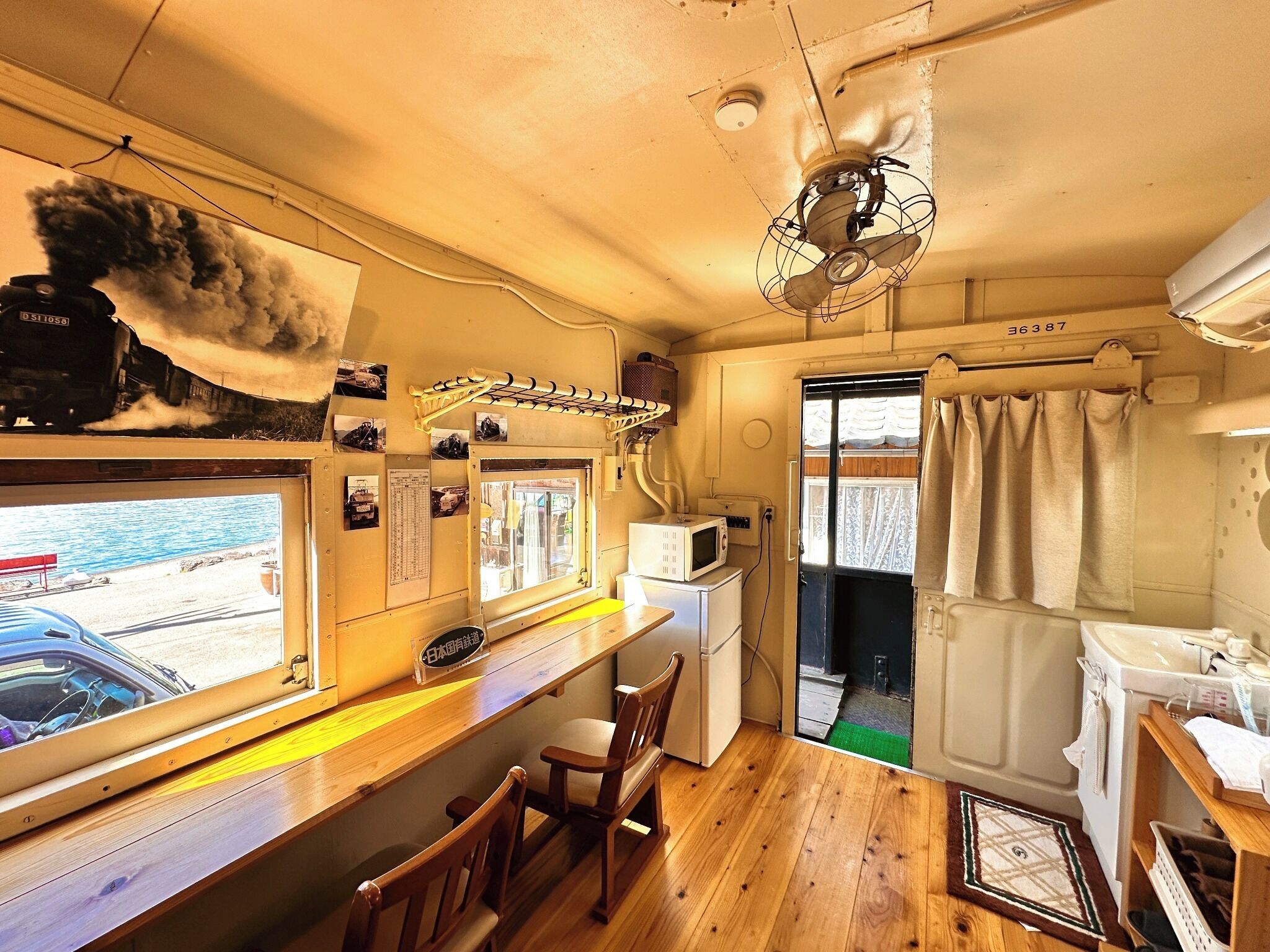 Una cocina compacta con encimera de madera, microondas, ventilador y vistas al mar.