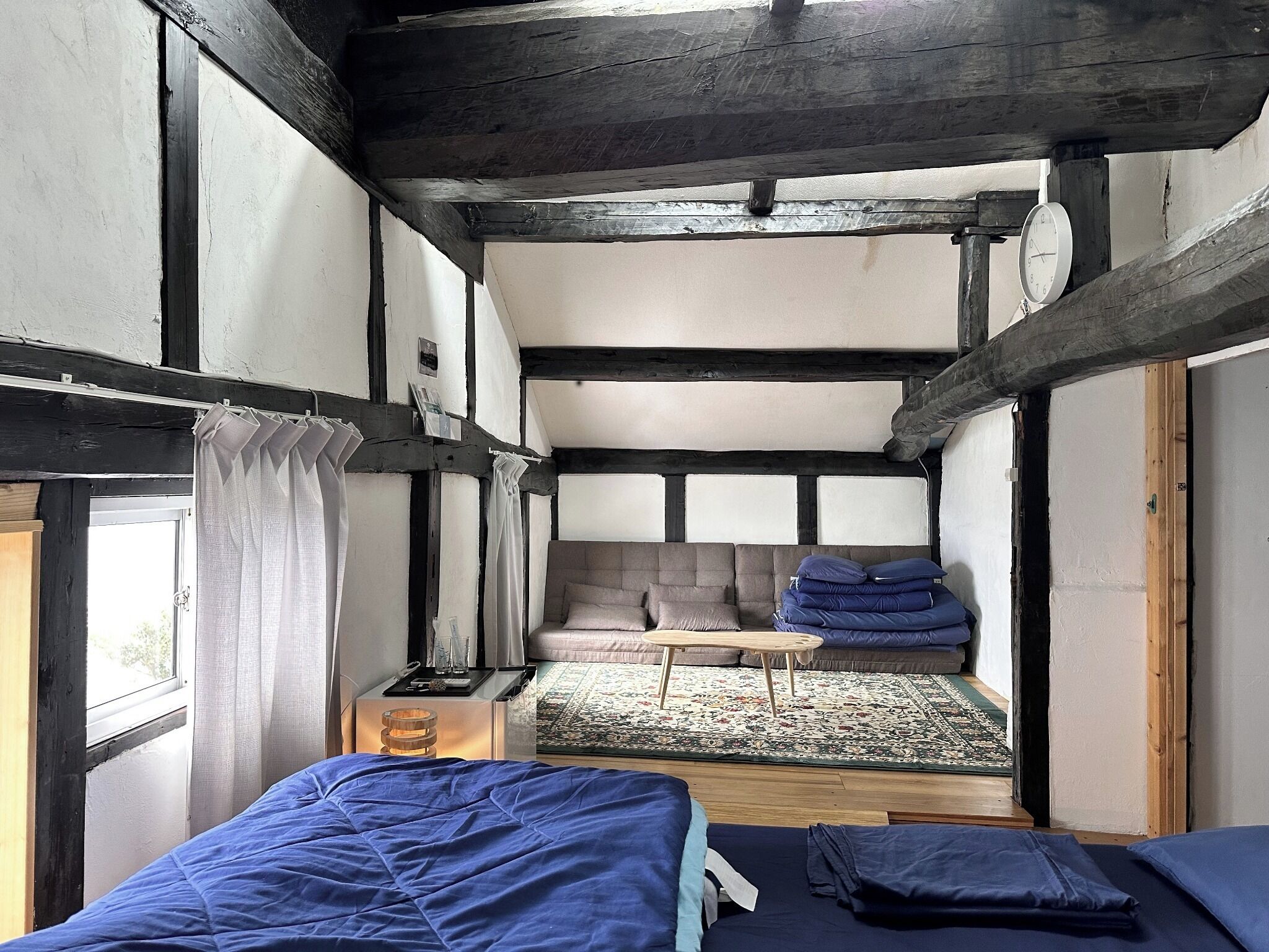 Una habitación con cama, una mesita, un sofá y una ventana.