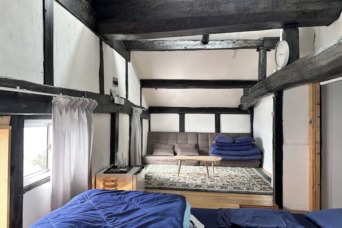 A room with a bed, a small table, a sofa, and a window.