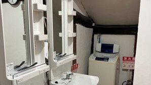 Baño con dos lavamanos, un espejo, un reloj y un extintor.