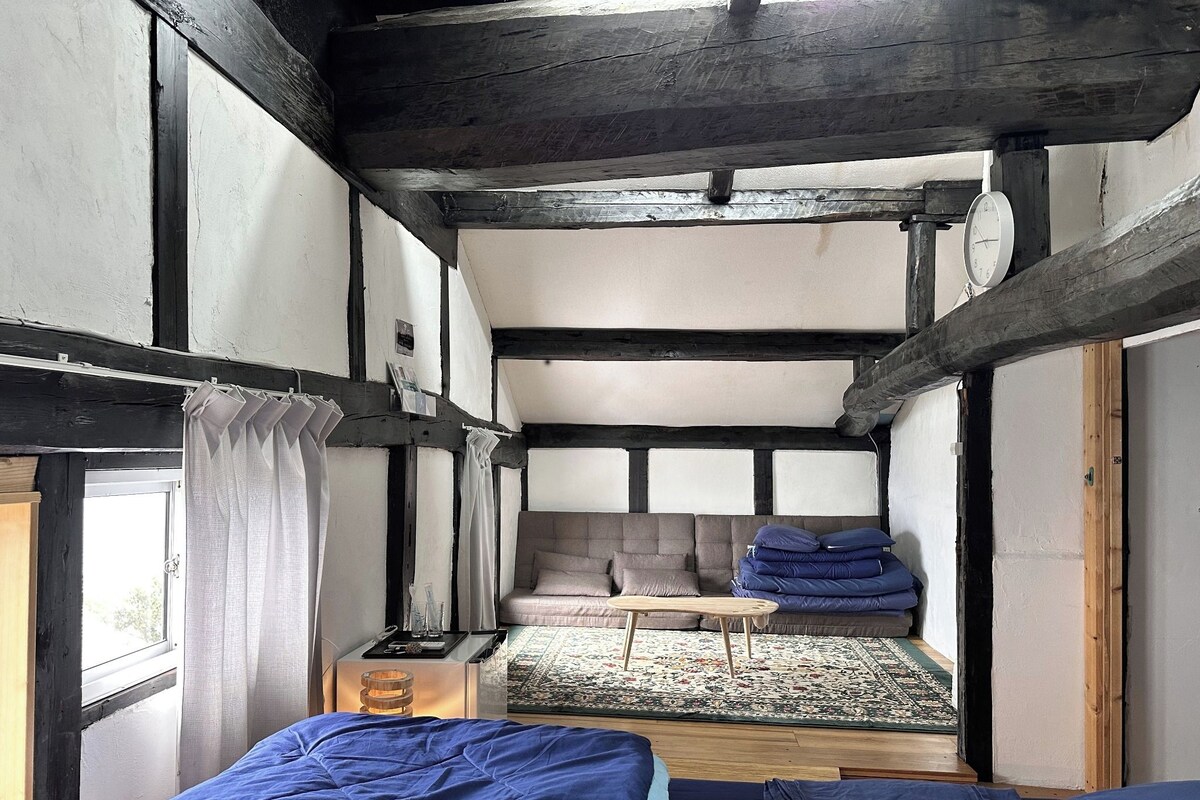 A room with a bed, a small table, a sofa, and a window.
