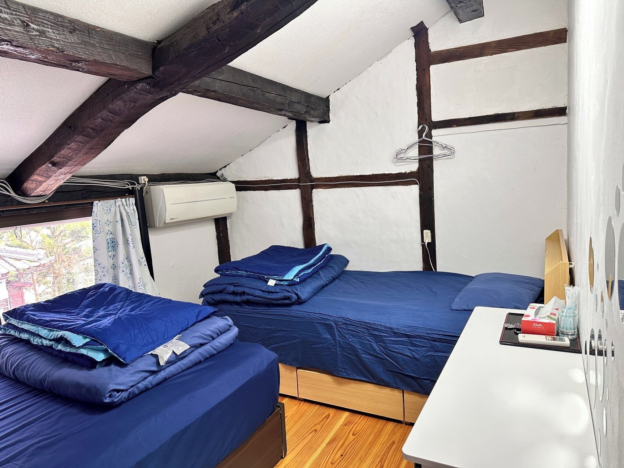 Una habitación pequeña y acogedora con dos camas, un escritorio y una ventana.