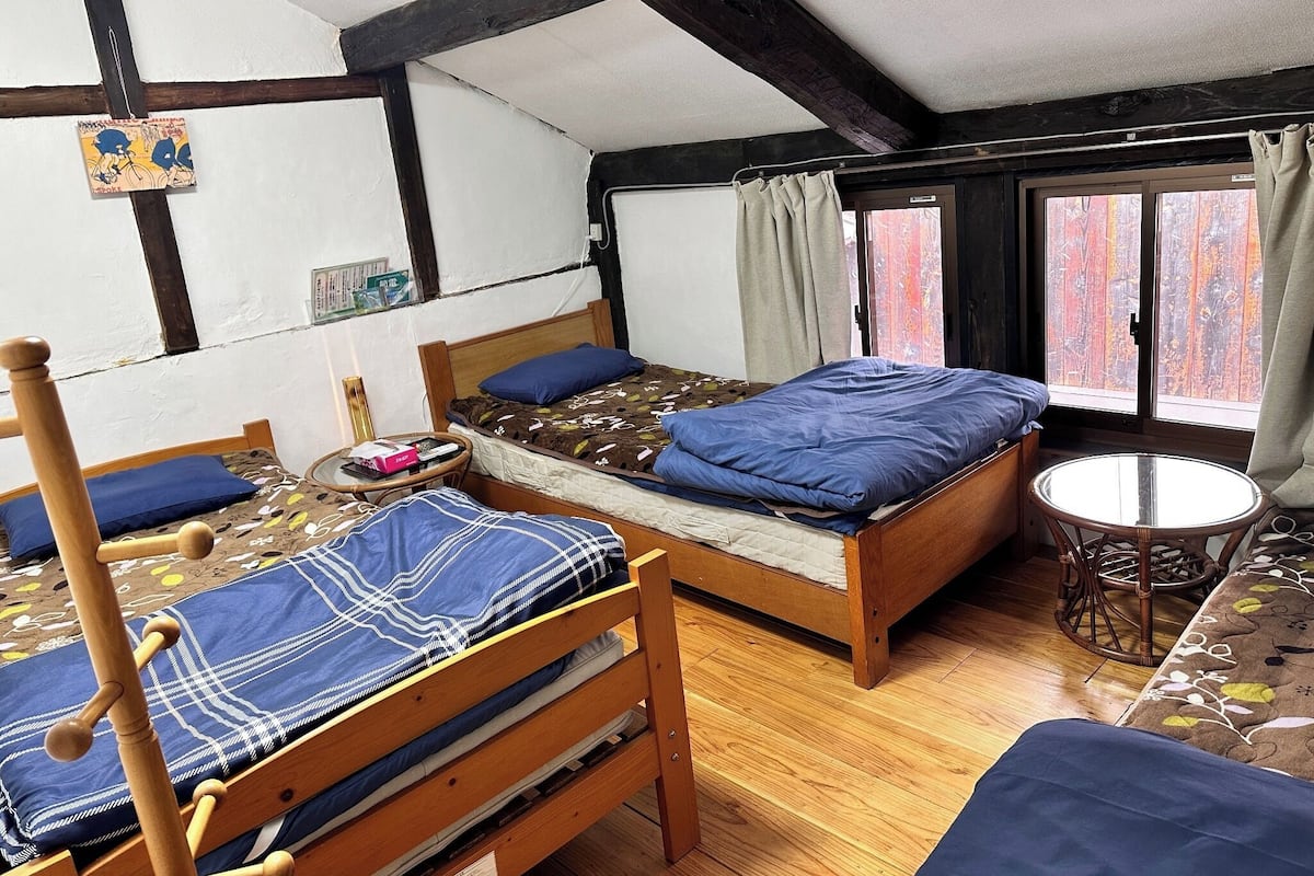 A room with two wooden beds, a small round table, and a window with curtains.