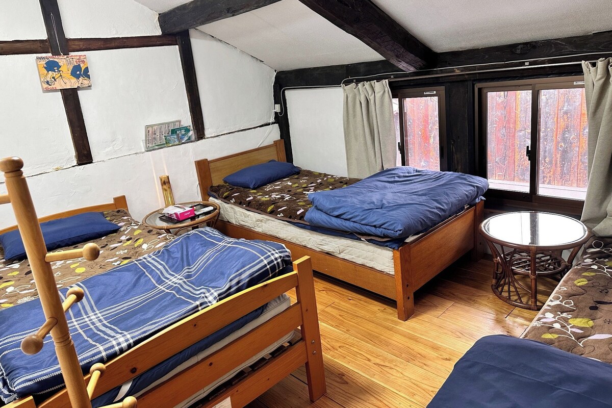 A room with two wooden beds, a small round table, and a window with curtains.