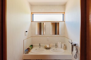 Une salle de bain avec deux lavabos, un miroir et un sèche-cheveux.