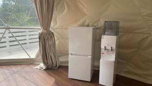 Een kamer met een raam, een witte koelkast en een waterdispenser.